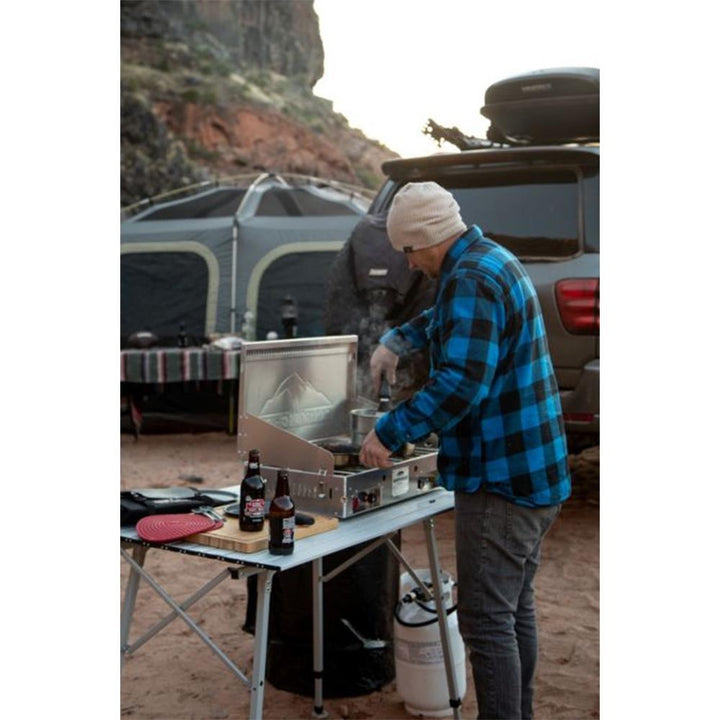 Chattanooga Camp Chef Mountaineer aluminum two-burner portable outdoor cooking system with sturdy metal surface and control knobs.